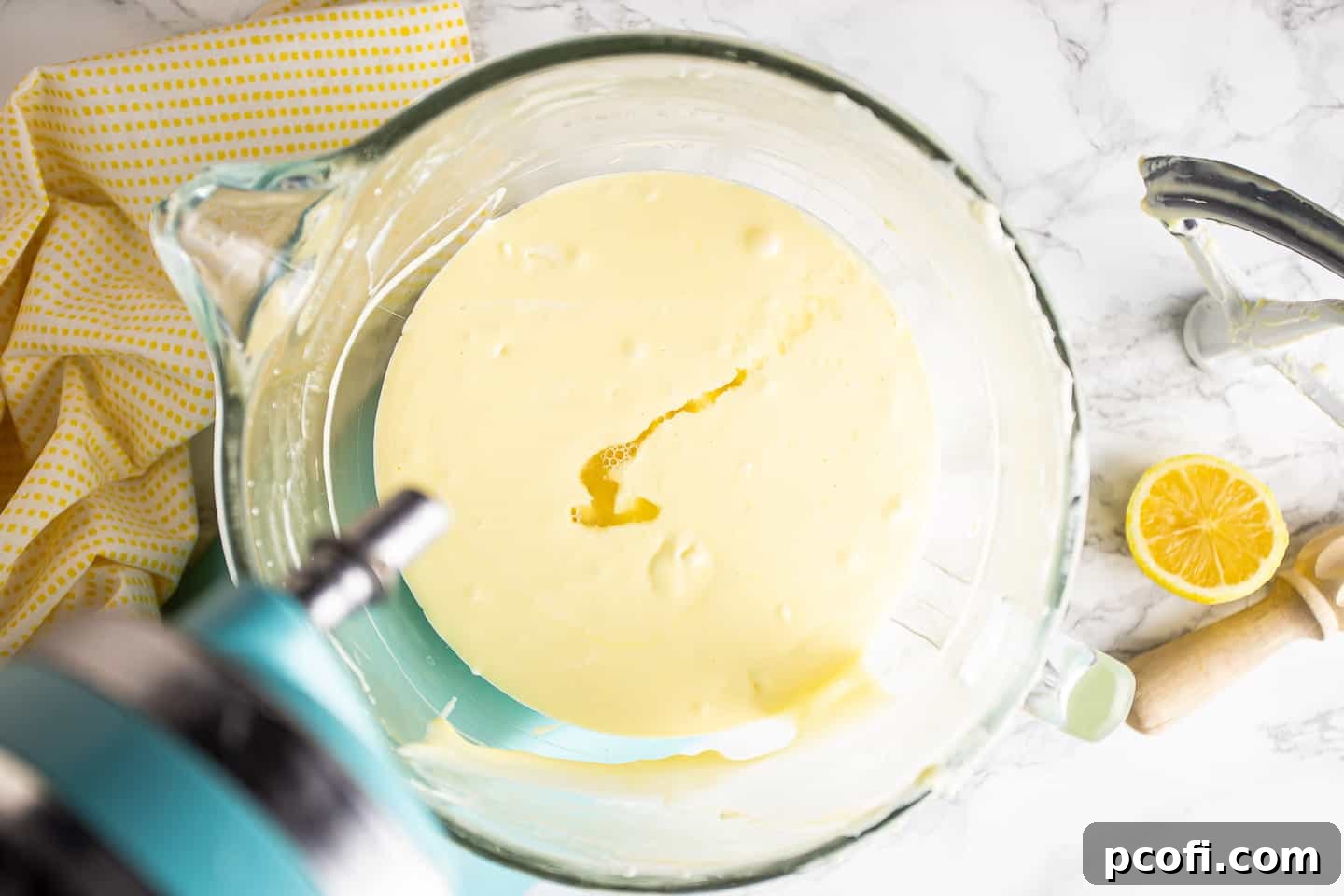 Pouring fresh lemon juice into the cheesecake batter, infusing it with bright, zesty flavor.