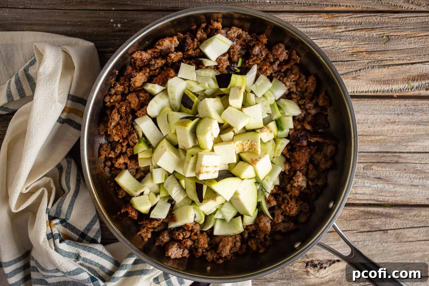 Process of adding vegetables to cooked Italian sausage in a pot.