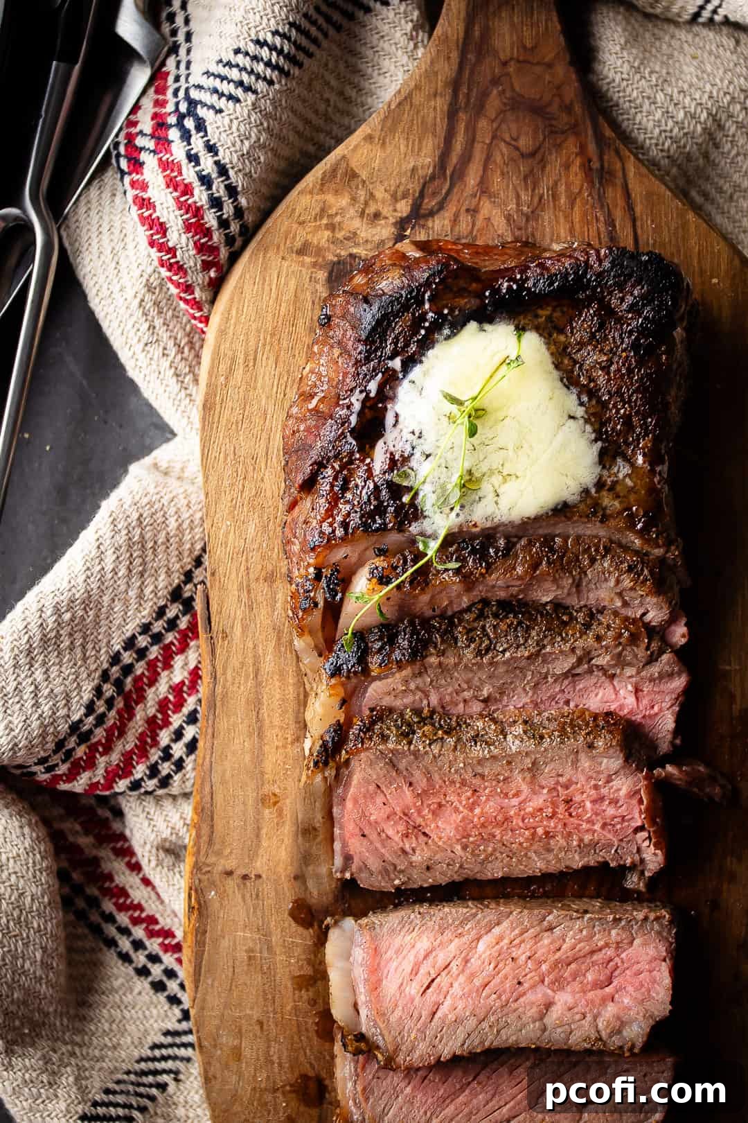 Reverse-seared steak presented on a wooden carving board.