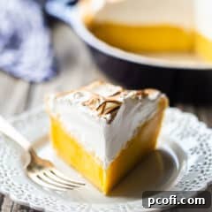 Lemon meringue pie on a lacy white plate.