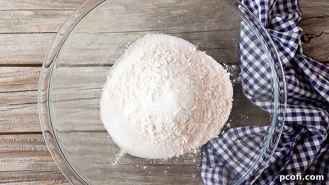 Dry ingredients for lemon meringue pie filling, including sugar, flour, cornstarch, and salt, meticulously combined in a large glass bowl.