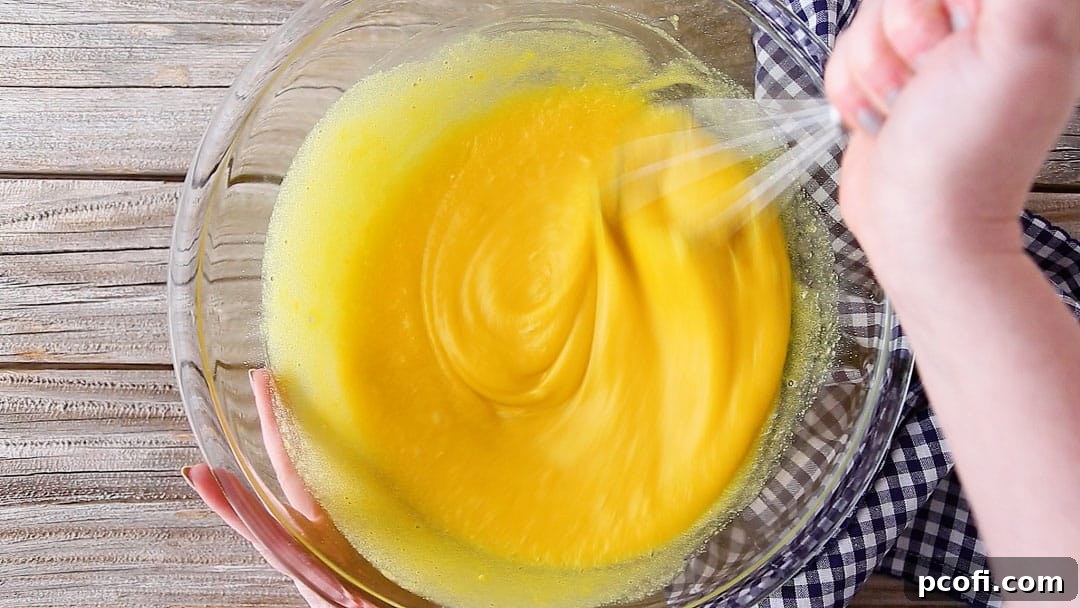 Smooth and lump-free lemon meringue pie filling mixture being whisked in a large glass bowl, ready for the fresh lemon juice.