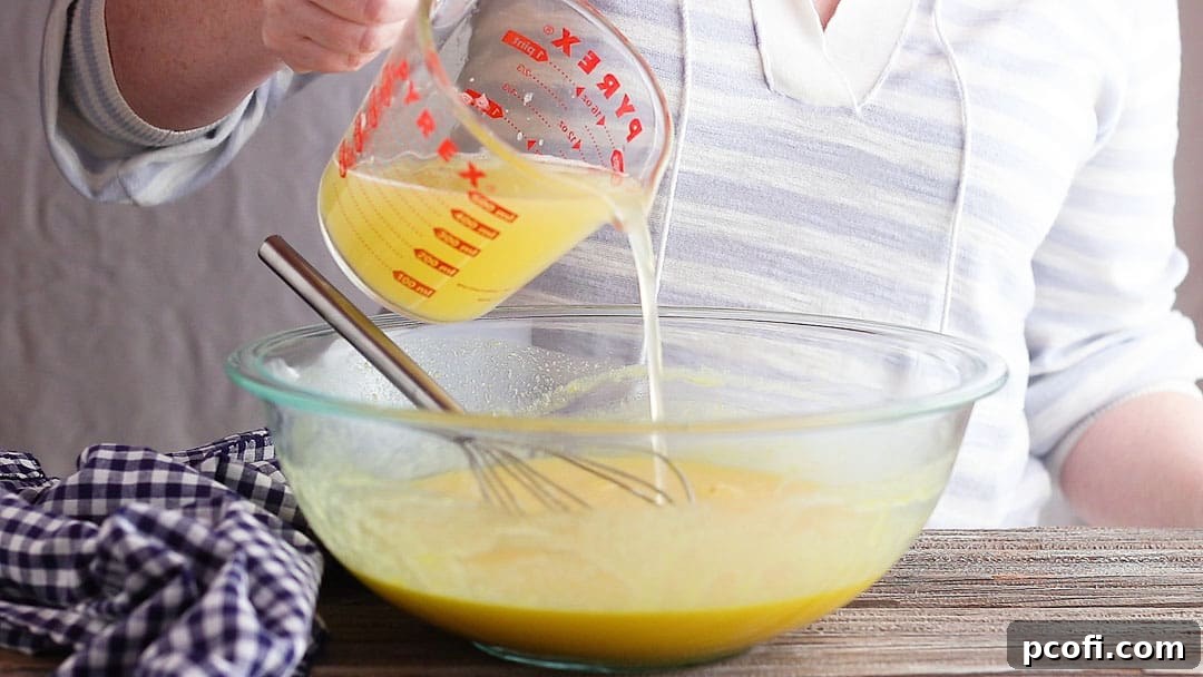 The vibrant lemon juice being whisked into the creamy egg mixture, creating the tangy foundation for the lemon meringue pie filling.