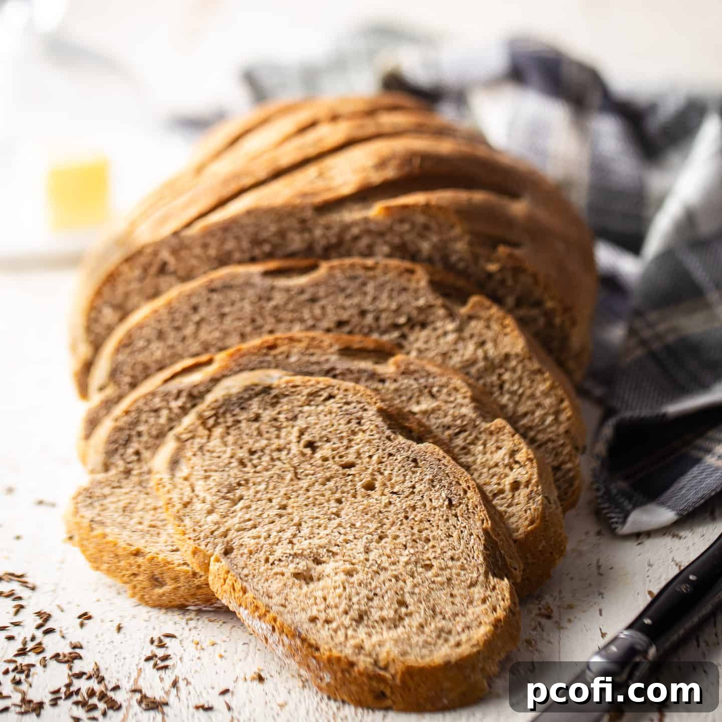A homemade loaf of rye bread, presented on a vintage white surface.