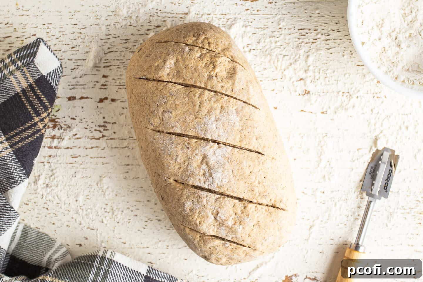 Slashing an unbaked rye bread loaf with a lame to allow steam to escape.
