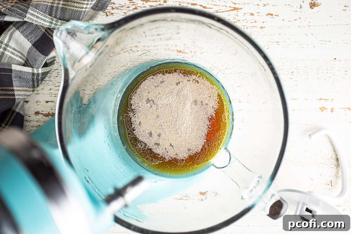 Sprinkling yeast over liquid ingredients.