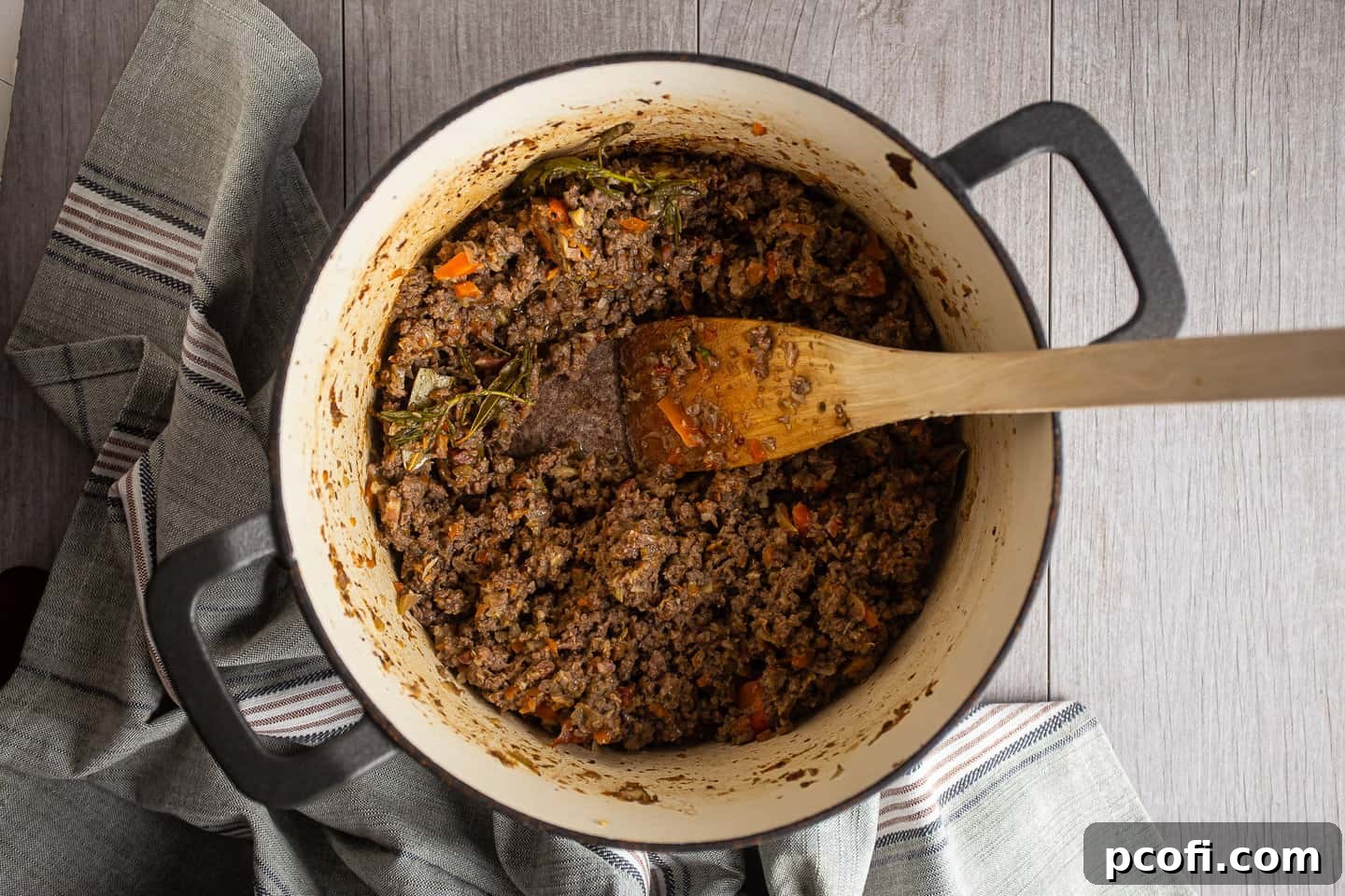 Bolognese ingredients simmering in a pot until all the milk has evaporated, leaving a thick base.