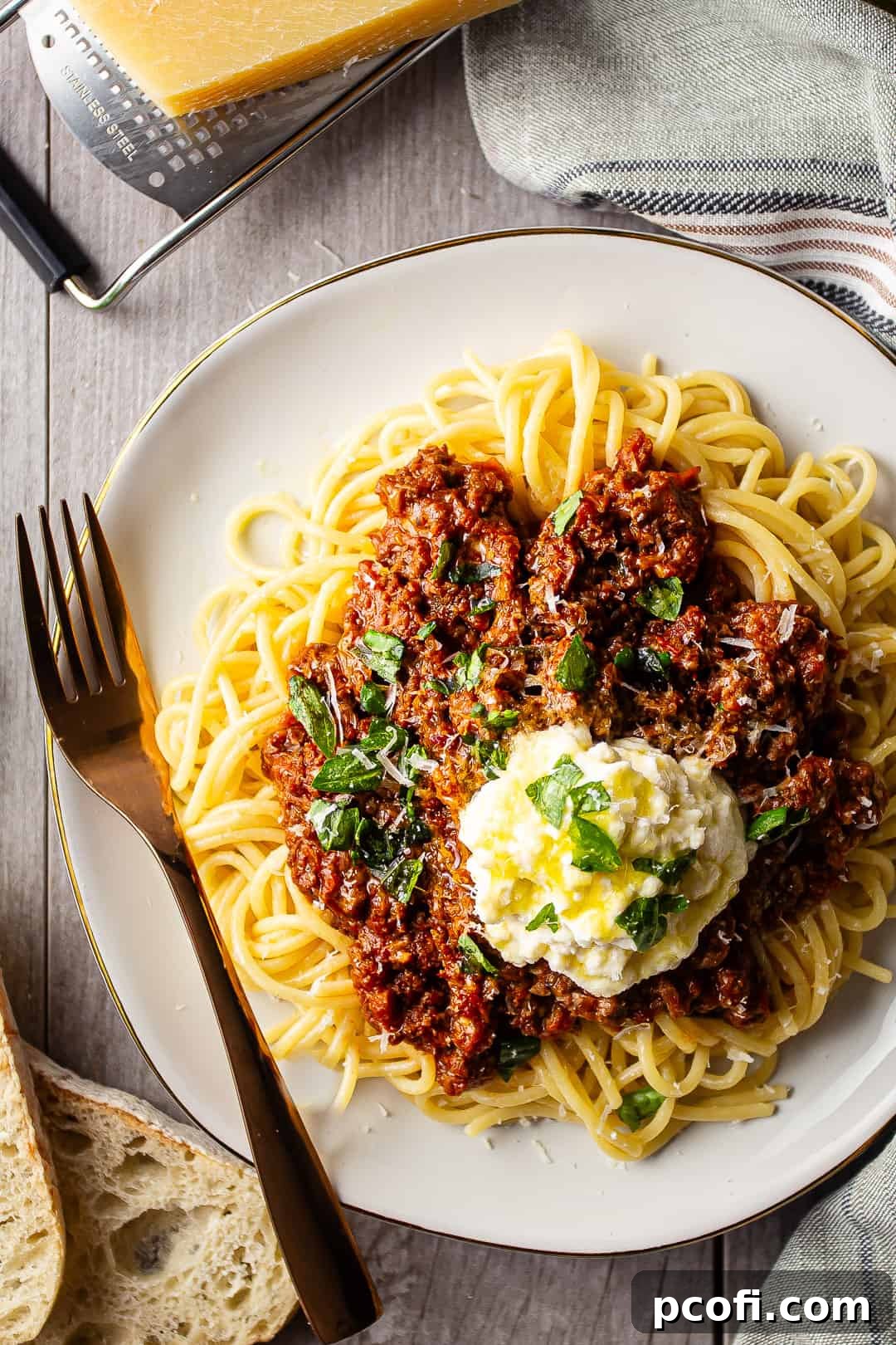 Bolognese sauce served over pasta, artfully drizzled with olive oil and sprinkled with parmesan cheese.