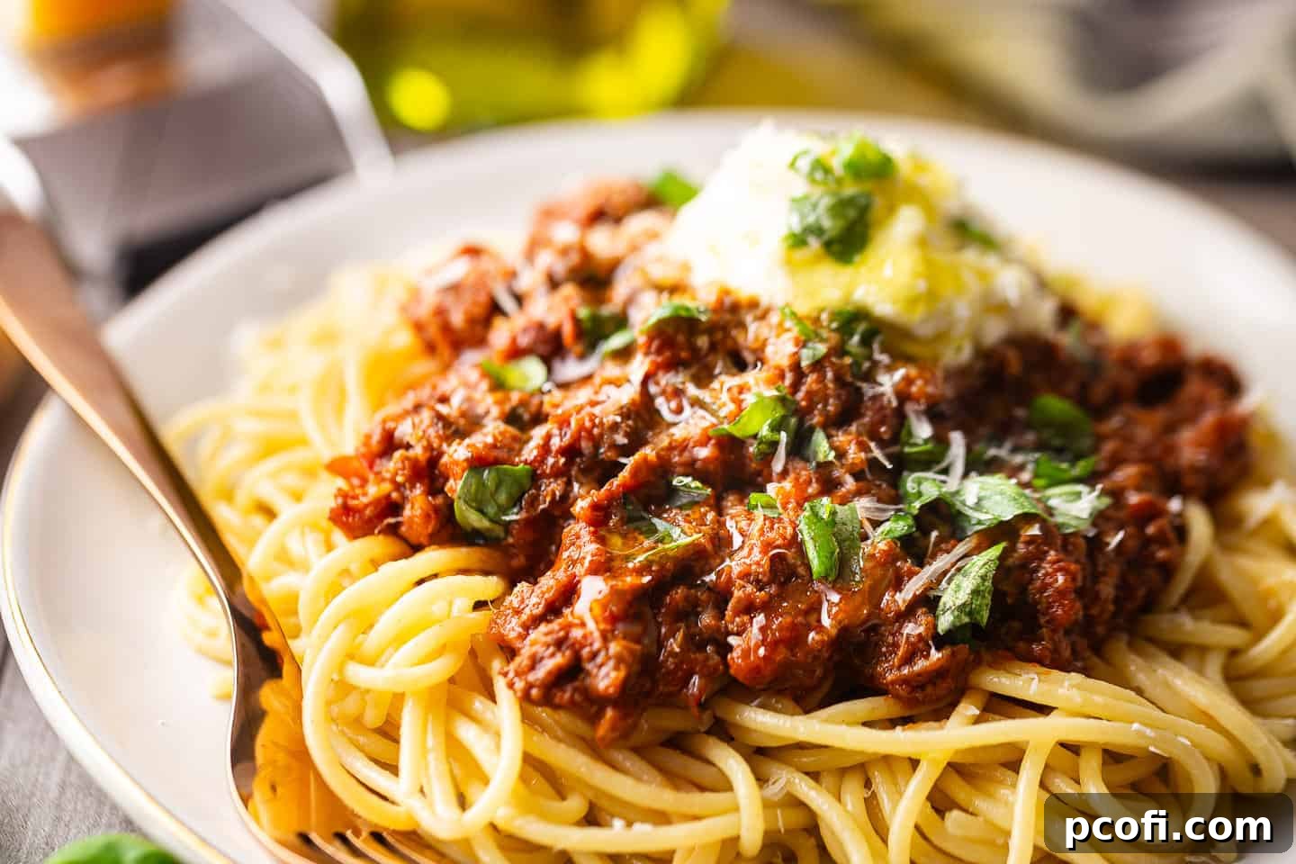 Spaghetti Bolognese generously garnished with fresh basil, creamy ricotta, grated parmesan, and a drizzle of olive oil.