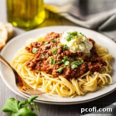 Bolognese sauce served over cooked spaghetti with a dollop of ricotta.