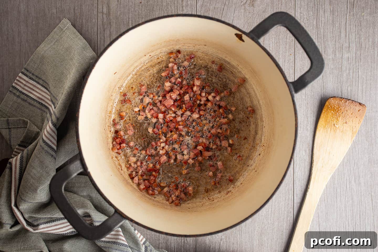 Diced pancetta cooking in a large pot, slowly rendering its fat to create a flavorful base.