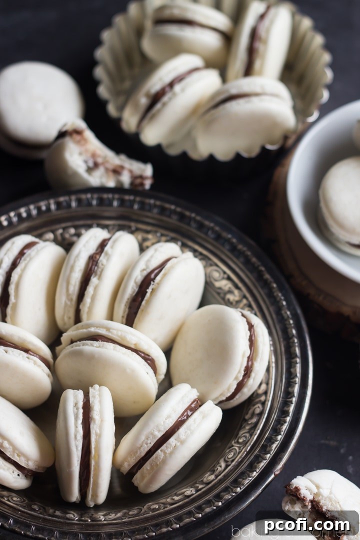 Close up of basic macaron shells cooling on a baking sheet, showcasing their characteristic 'feet'.