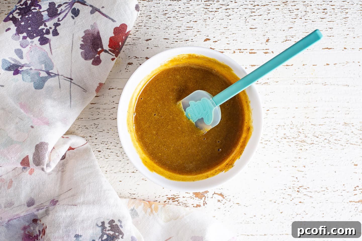 The ham glaze ingredients – brown sugar, Dijon mustard, and ground cloves – are being thoroughly stirred together in a bowl to create a smooth, consistent mixture.