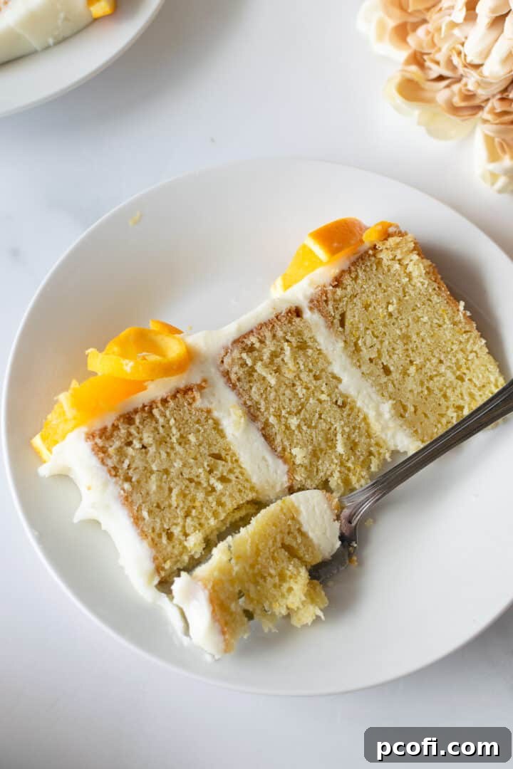 Two slices of orange creamsicle cake on a plate, showing the three layers of cake and frosting.