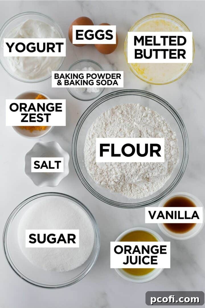 A selection of fresh oranges, butter, flour, and baking ingredients laid out on a surface.