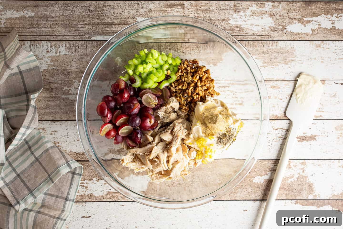 Chicken salad ingredients in a large glass mixing bowl.