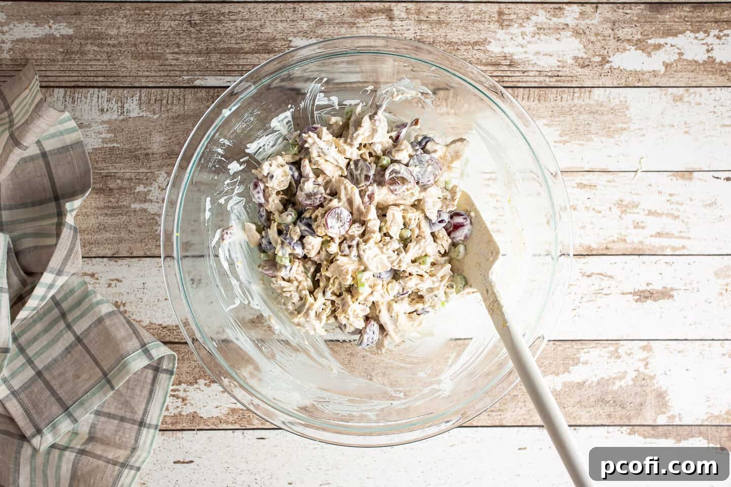 Mixing up chicken salad in a large bowl with a silicone spatula.