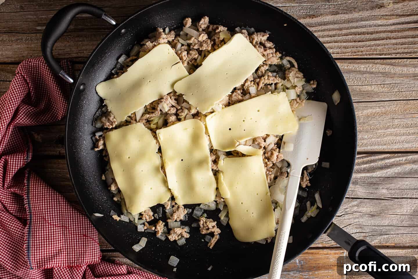 Melting cheese over chicken cheesesteak sandwich filling.