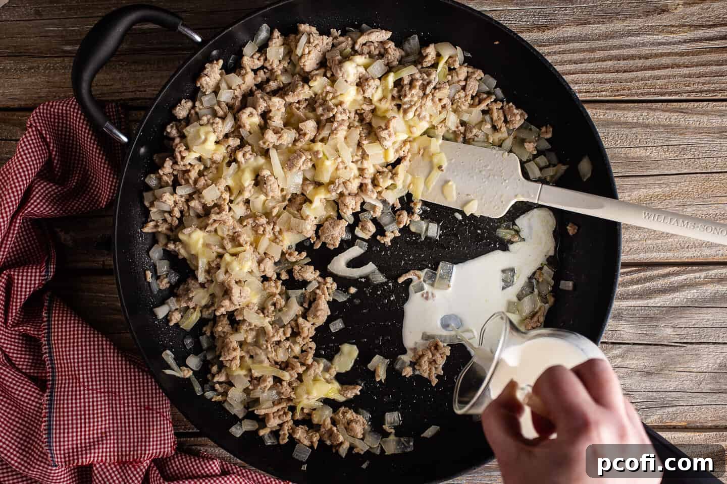 Adding liquid to chicken cheese steak sandwich to create a sauce.