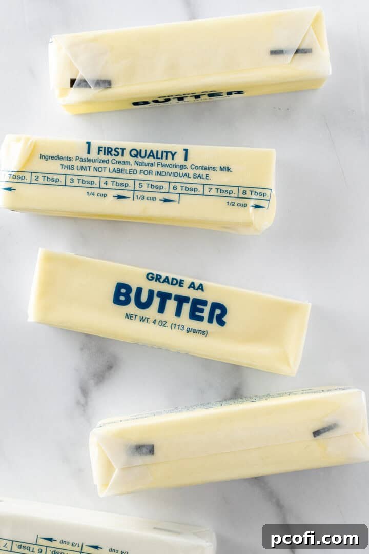 Five sticks of butter set out on a white counter, ready to be softened for baking perfection.