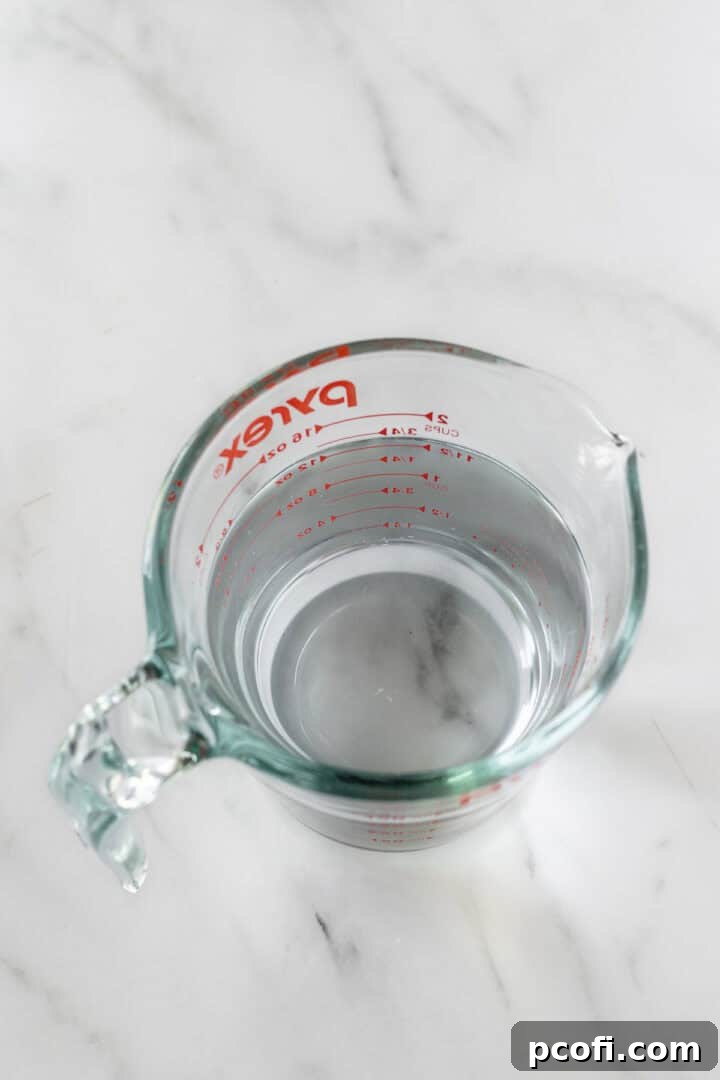 A liquid measuring cup filled with hot water, used to create steam for softening butter in the microwave.