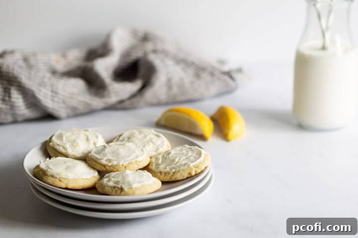 Frosted lemon cookies on a plate next to a bottle of milk.