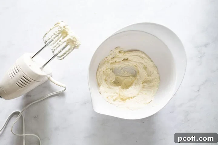 Frosting in a bowl next to a hand mixer.