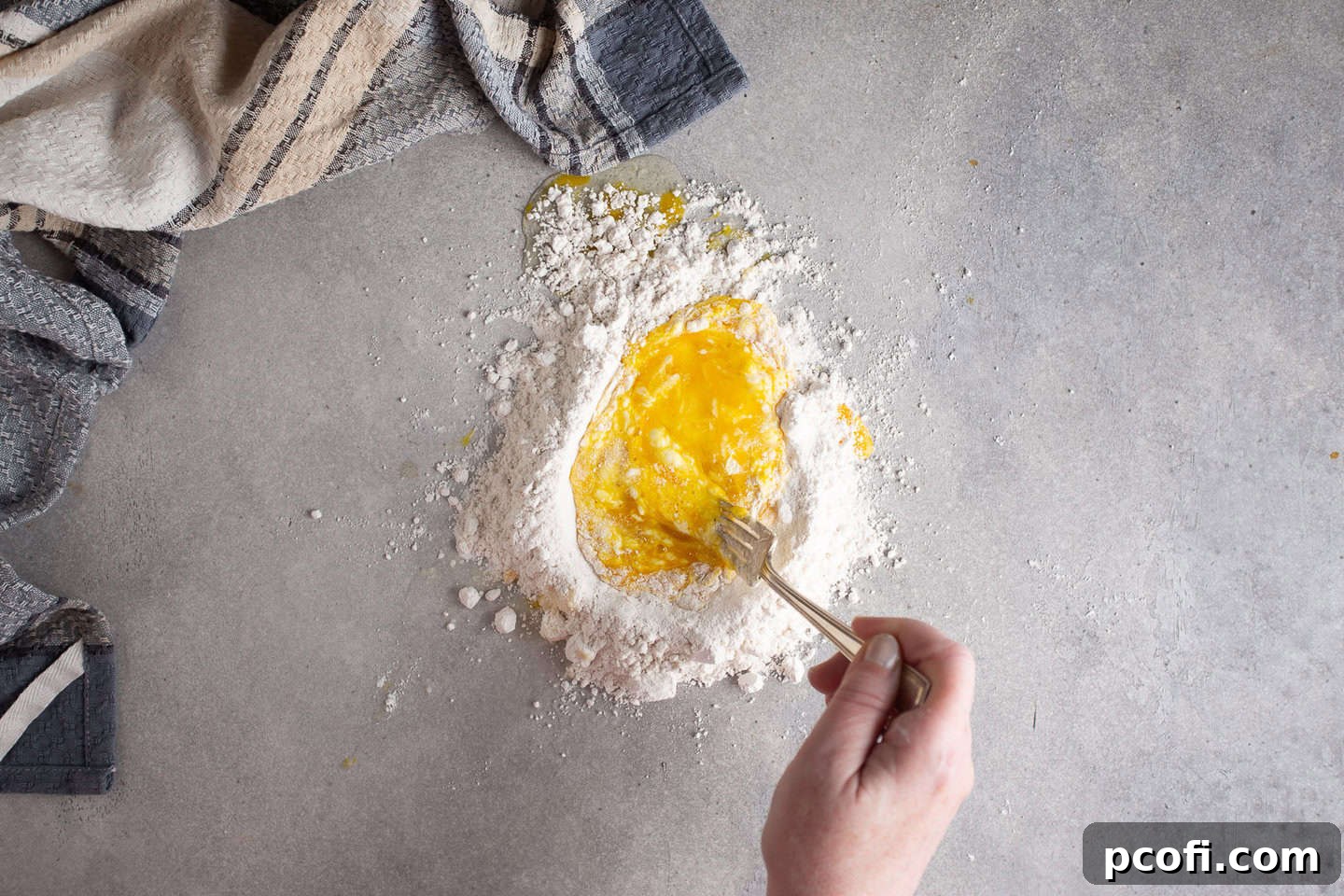 Whisking eggs into flour to make a dough, showing the initial mixing process.