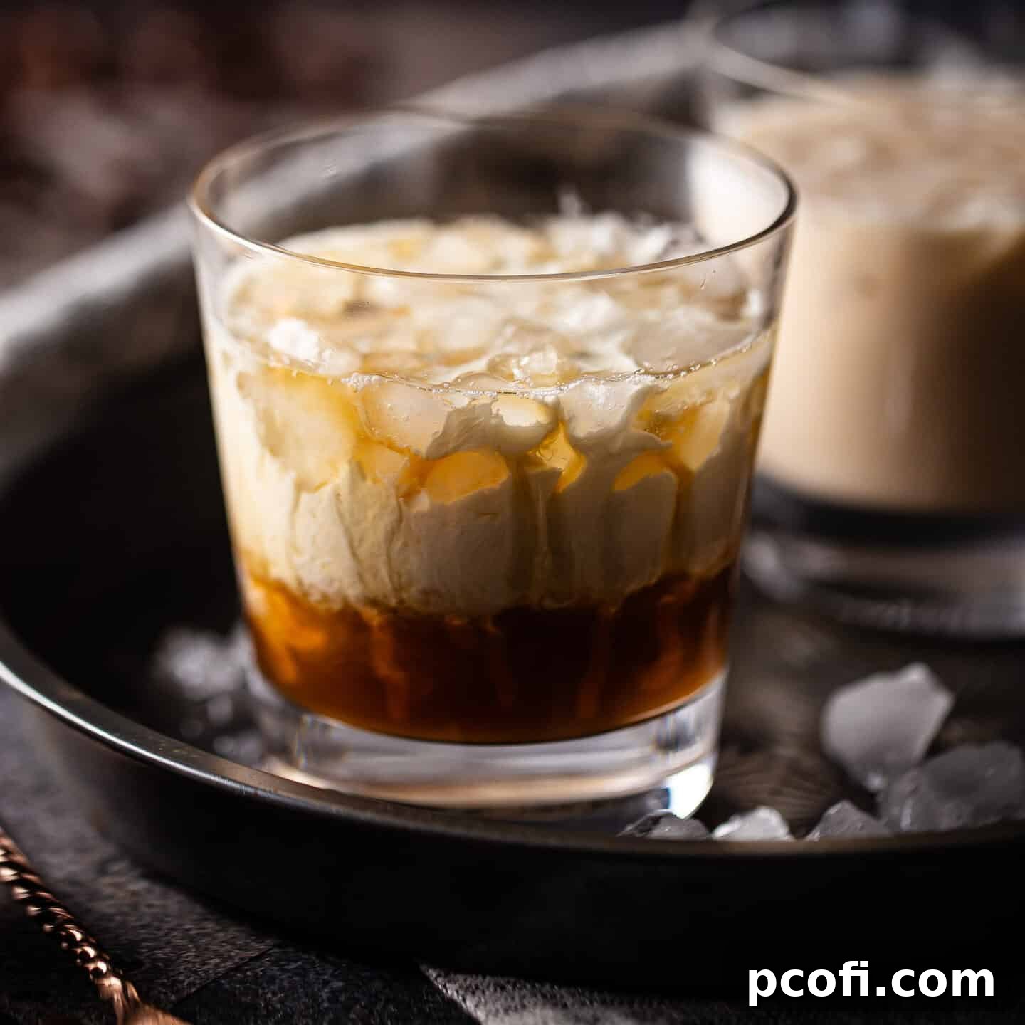 White Russian cocktail in a low ball glass with crushed ice, garnished with coffee beans.