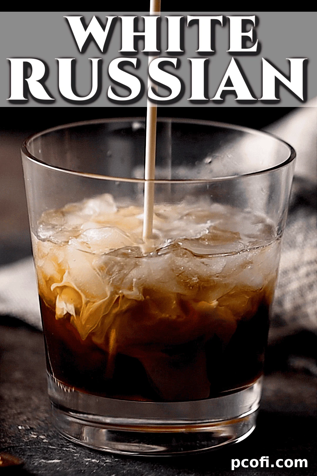 Pouring fresh cream into a white Russian recipe in a glass.