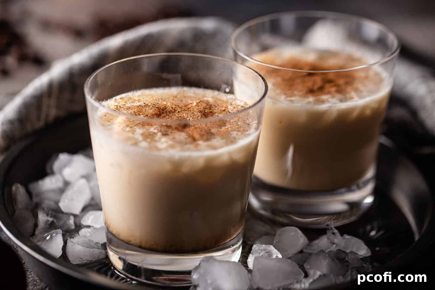 White Russian drinks presented in a vintage cake pan with crushed ice, garnished with cocoa.