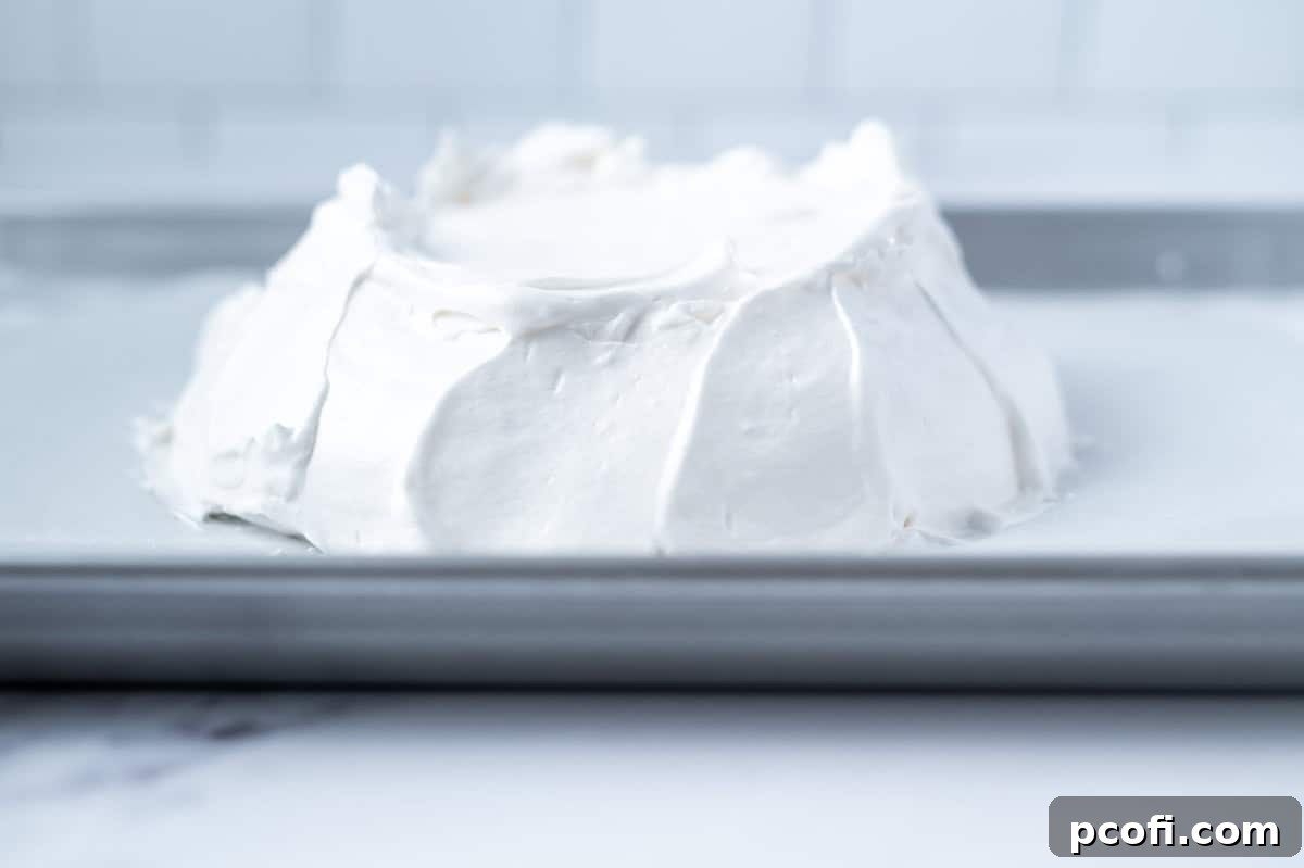 swooping shaped sides of unbaked pavlova on a baking pan
