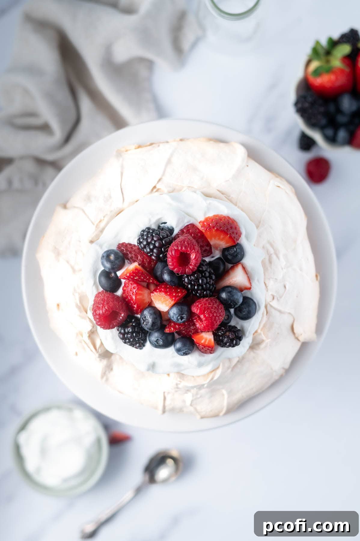 overhead look at berries and whipped cream topping on pavlova