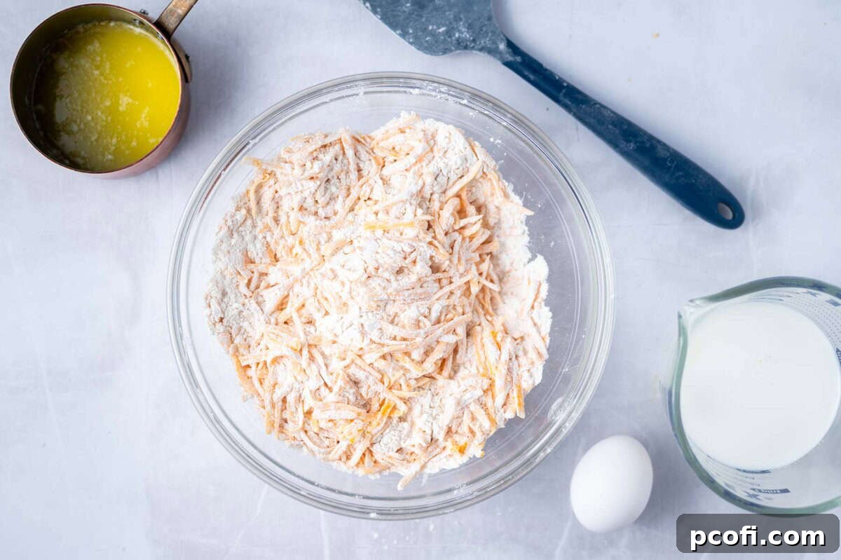 dry ingredients tossed with cheddar cheese in a mixing bowl