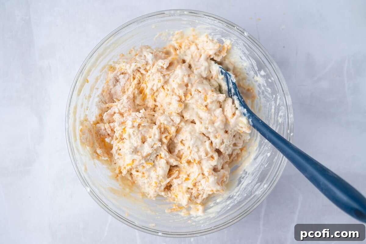 cheese bread batter in a glass mixing bowl with a spatula