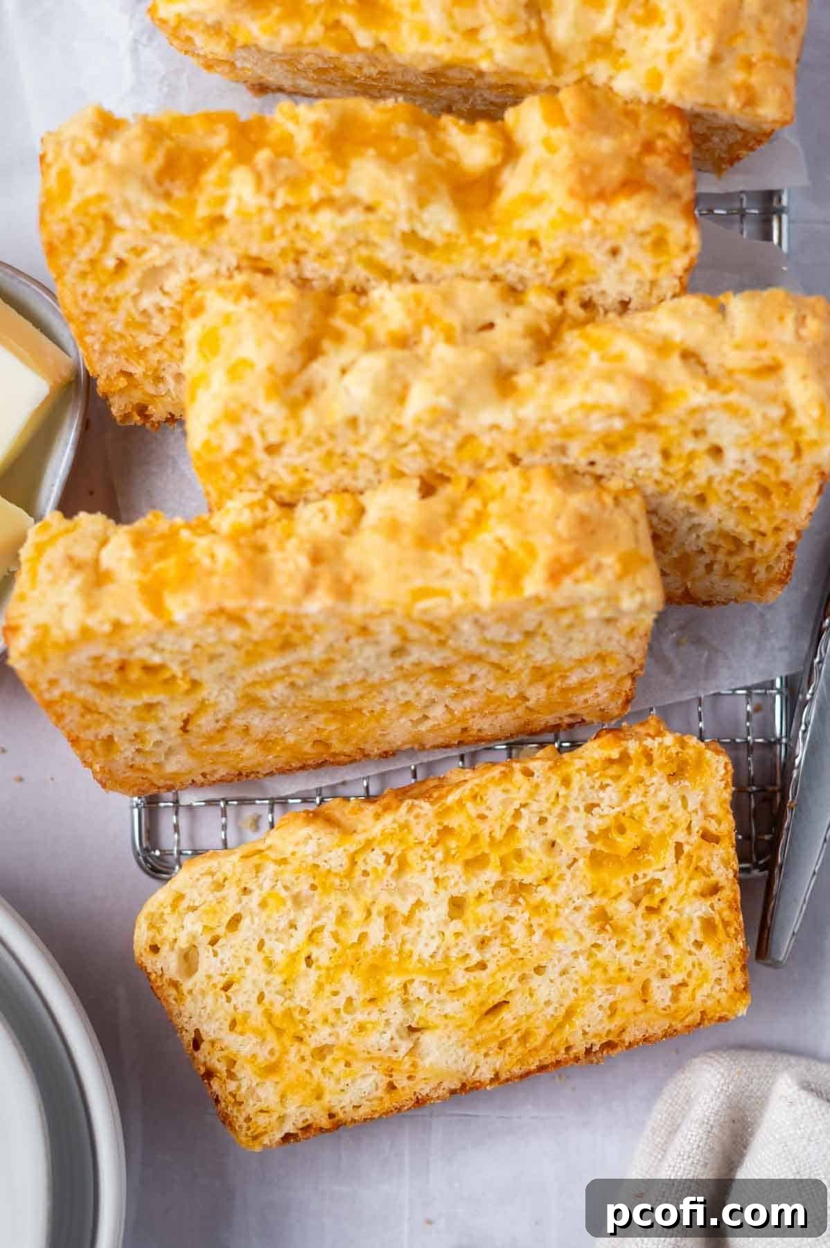 slices of cheese bread on a cooling rack with plates and butter on the side.