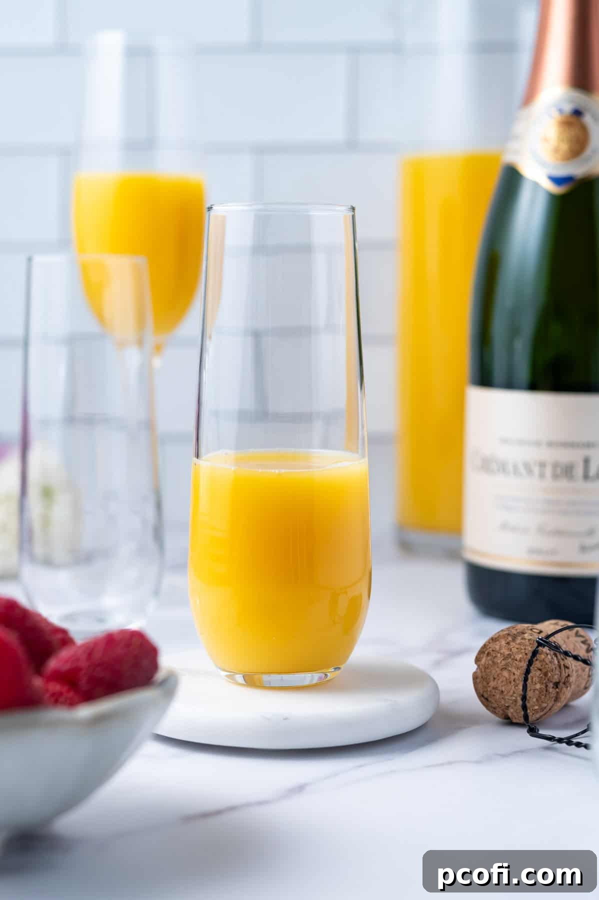Stemless champagne flute half filled with bright orange juice.