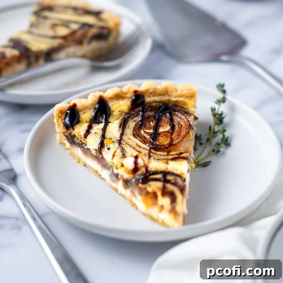 slice of onion tart garnished with balsamic gaze and thyme on a plate