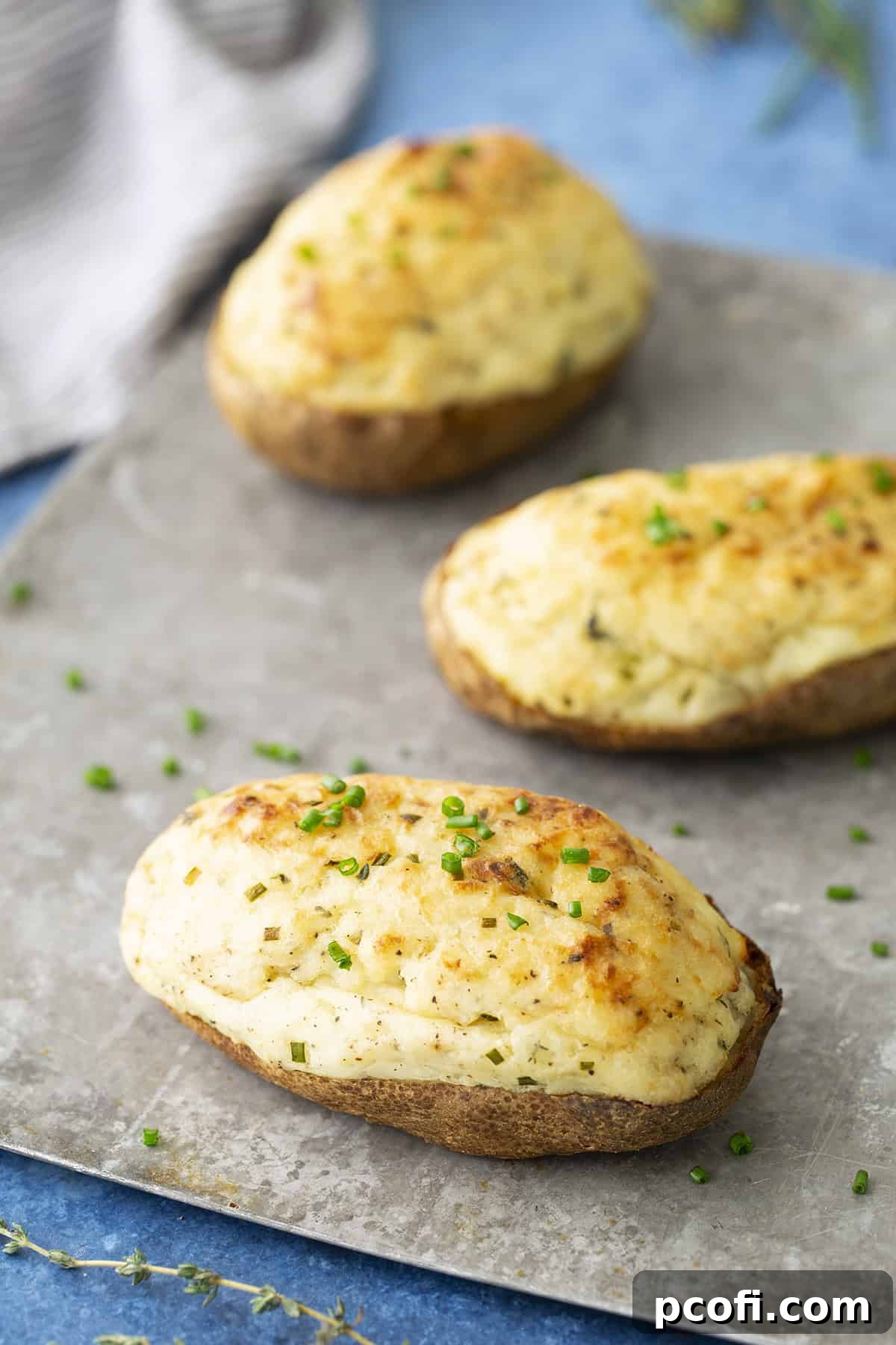 Twice-baked potatoes on a sheet pan, showcasing golden, crispy skins and a fluffy, creamy filling