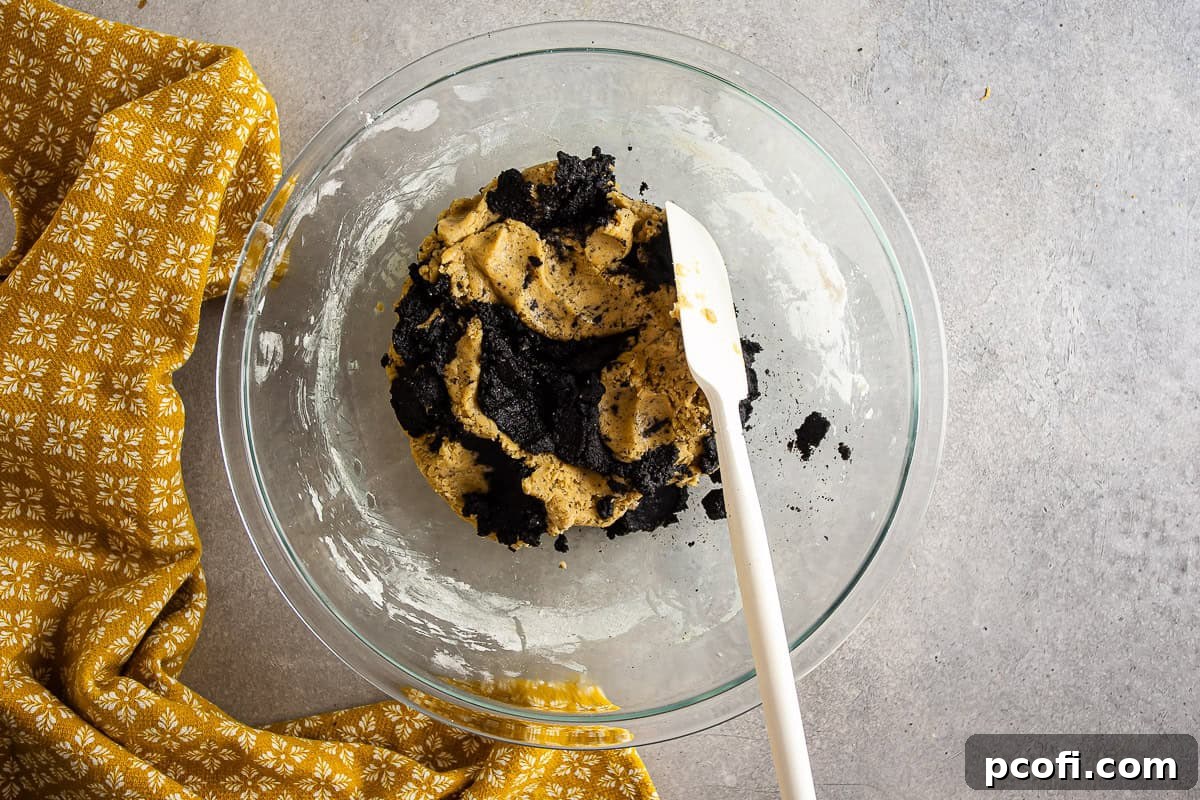 Swirling the black tahini into the Earl Grey cookie dough, creating distinct dark streaks.