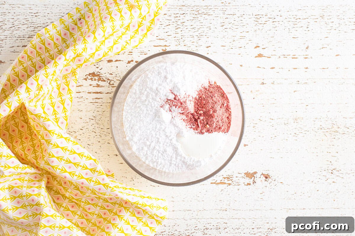 Smooth, pink strawberry icing in a bowl, ready to be drizzled over the loaf.