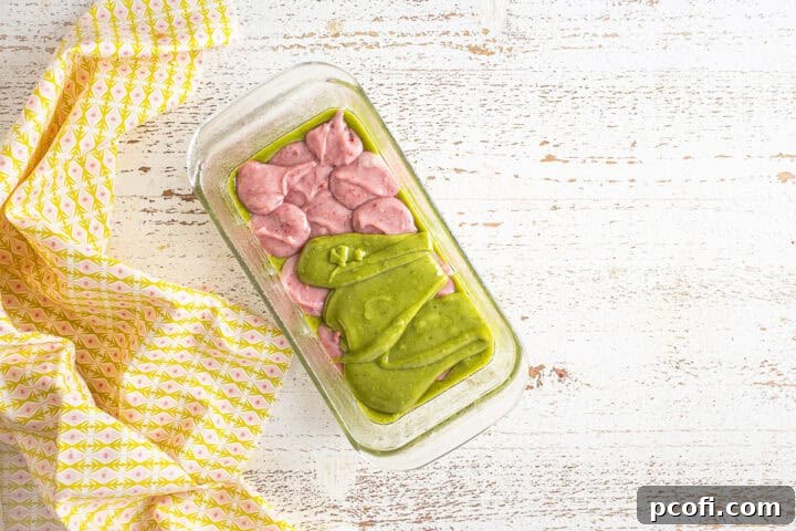 Alternating layers of pink strawberry and green matcha batter building up in the loaf pan.