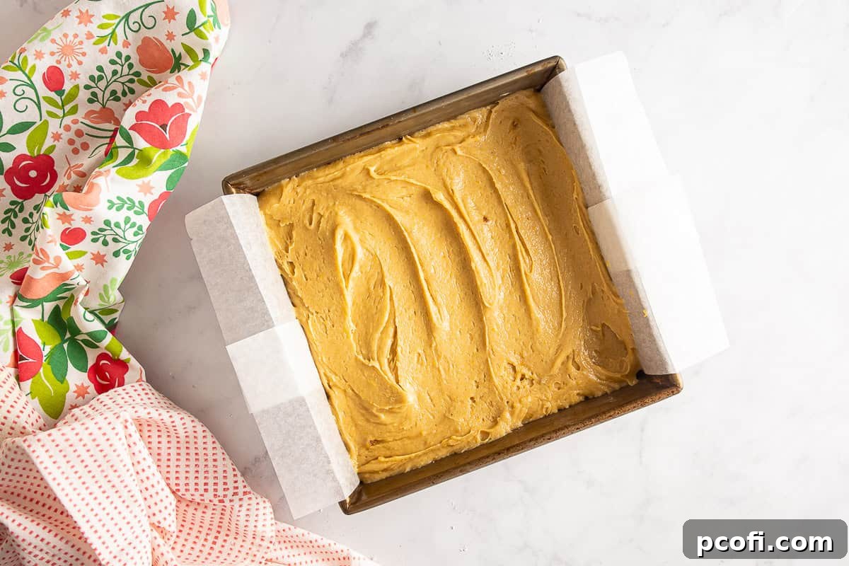 Blondie batter smoothly spread in a prepared 9x9 inch baking pan.