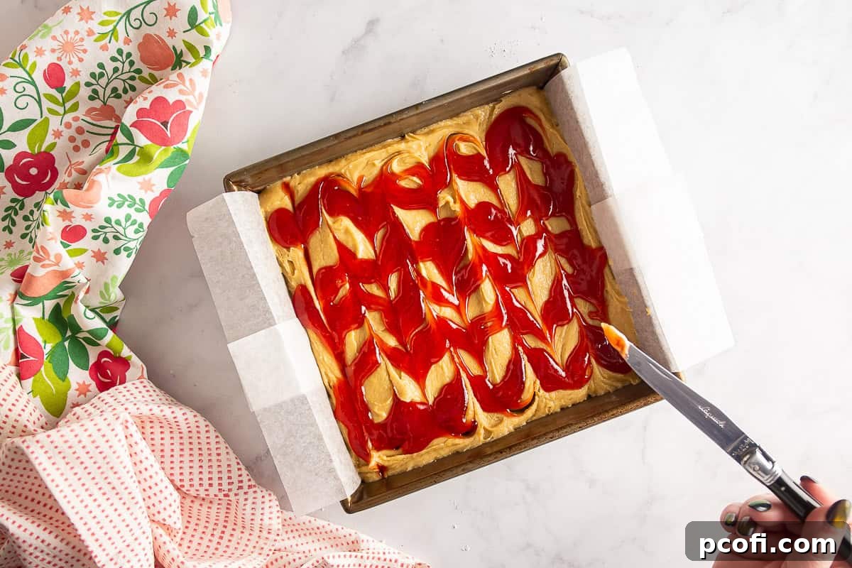 Strawberry jam beautifully swirled into the blondie batter, creating an artistic pattern before baking.