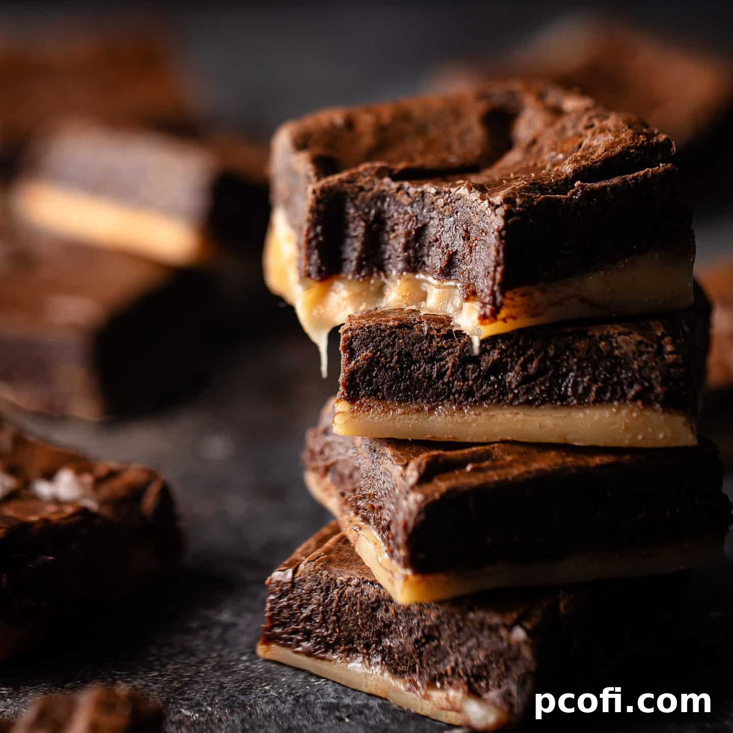 Salted caramel brownies stacked on top of one another, showing gooey caramel layers.