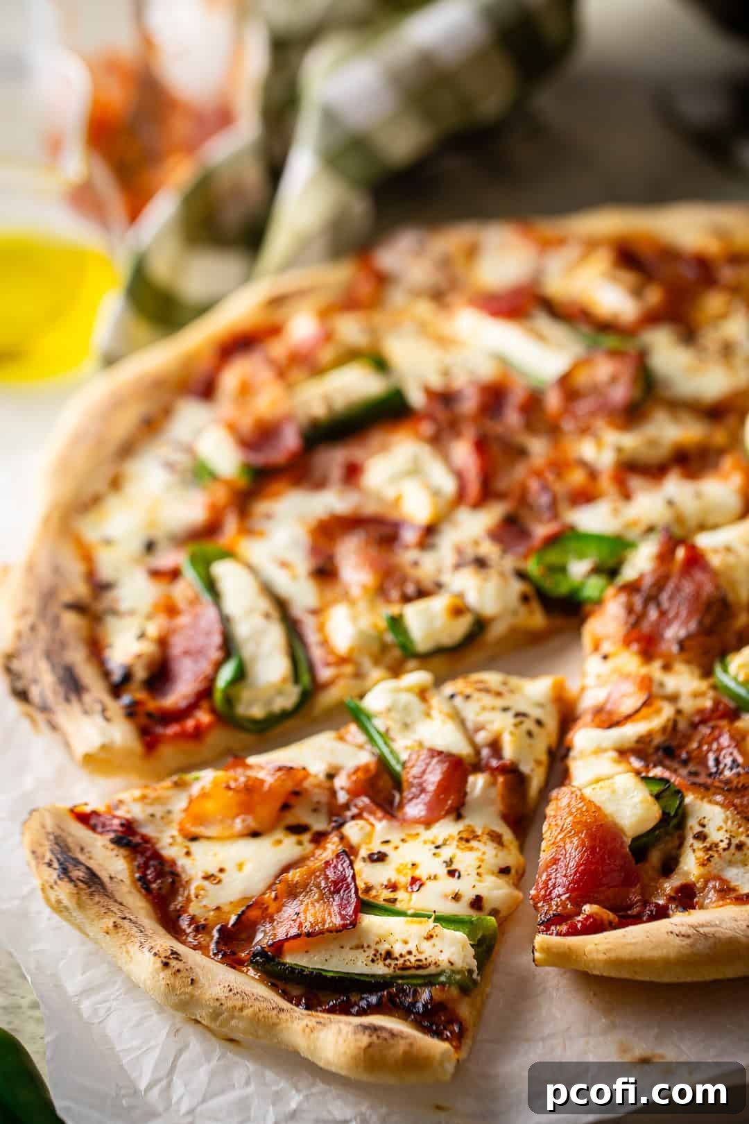 A jalapeno popper pizza with a slice partially removed, showing the creamy filling and crispy bacon.