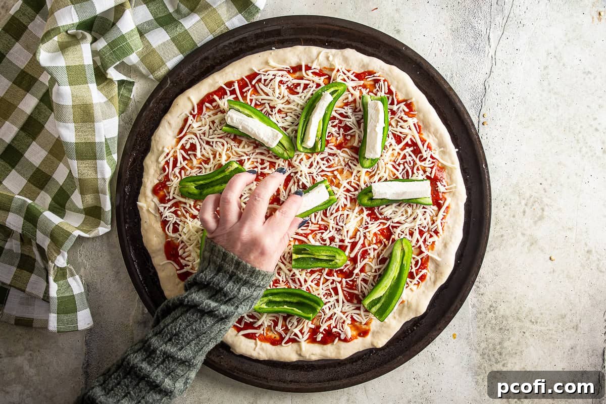 Adding cream cheese stuffed jalapenos to the top of the pizza before baking.