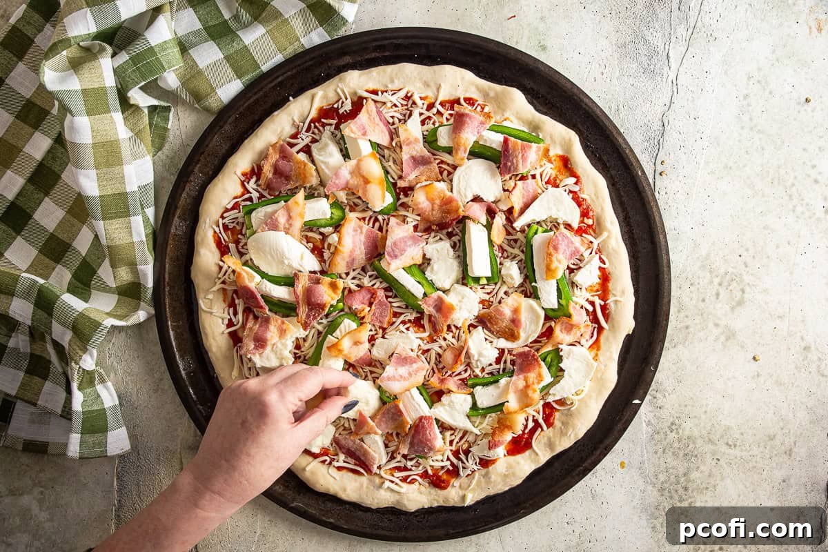 Finishing the topping of the pizza with fresh mozzarella before it hits the oven.