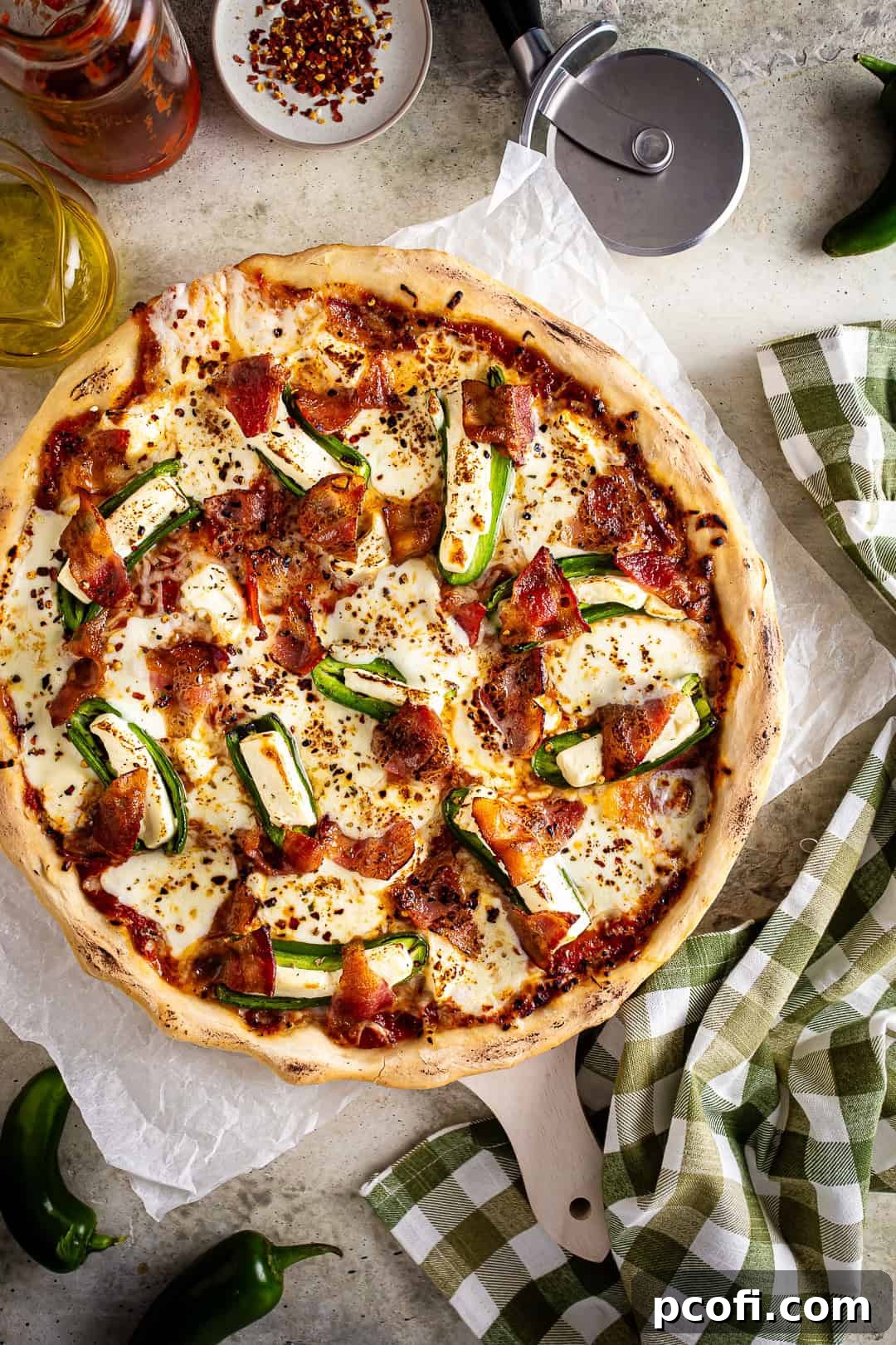 Jalapeno popper pizza after being baked but before being cut, showcasing golden crust and melted cheese.