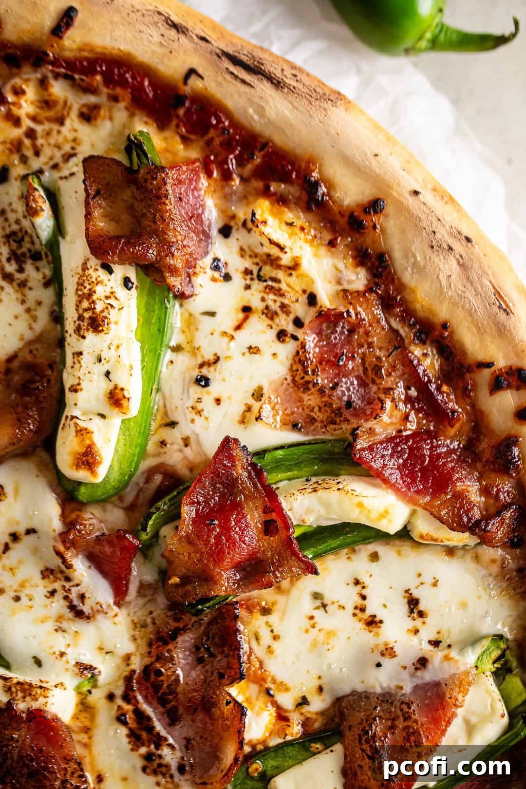 Close-up of a slice of jalapeno popper pizza, showing the texture of the crust, melted cheese, and bacon.